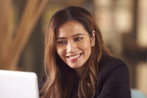 Mujer sonriendo y trabajando en su laptop